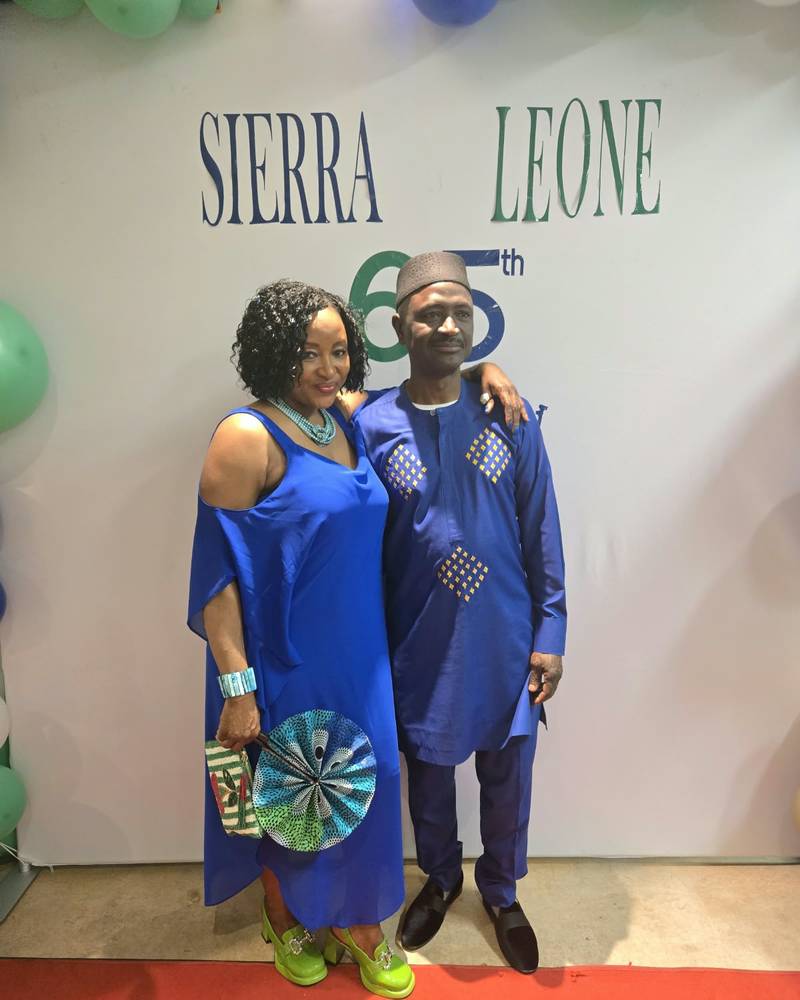 Two guests in matching royal blue outfits on the red carpet in front of the Sierra Leone 65th backdrop