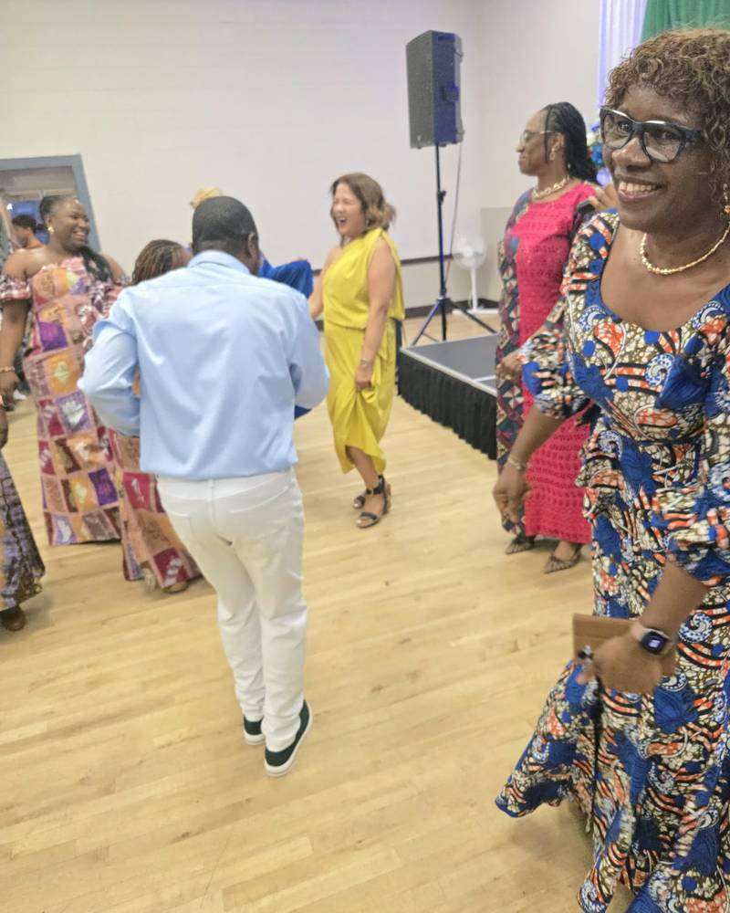 A smiling guest in a blue and orange print dress on the dance floor at SALONE@65