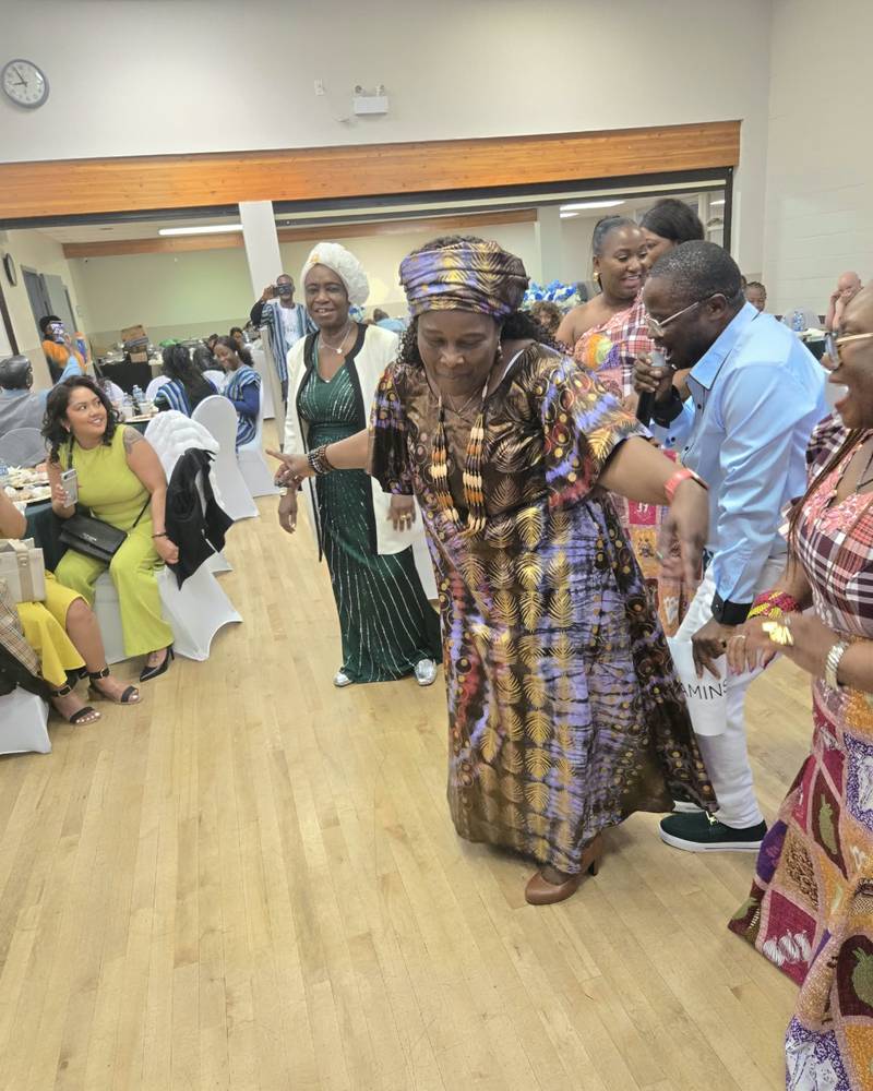 A guest in a gold and purple gown and head wrap dancing at SALONE@65