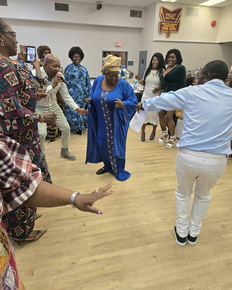 A guest in a blue gown dances in the middle of a circle of guests at SALONE@65